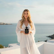 Woman holding House of DaVoice Lemon Blue Sky perfume inspired by Dolce and Gabbana Light Blue Perfume for Women overlooking the Mediterranean coast