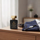 House of DaVoice Mountain Wind Sauvage dupe sitting beside a navy blazer and men's accessories