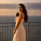 Woman holding Vanilla Tide 100 mL perfume that is a Brazilian Crush 62 dupe at a luxury resort at sunset