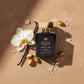 A perfume bottle labeled 'House of DaVoice Vanilla Tide Eau de Parfum' is arranged on a warm beige surface with a white flower, vanilla bean, pistachios, and sea salt scents