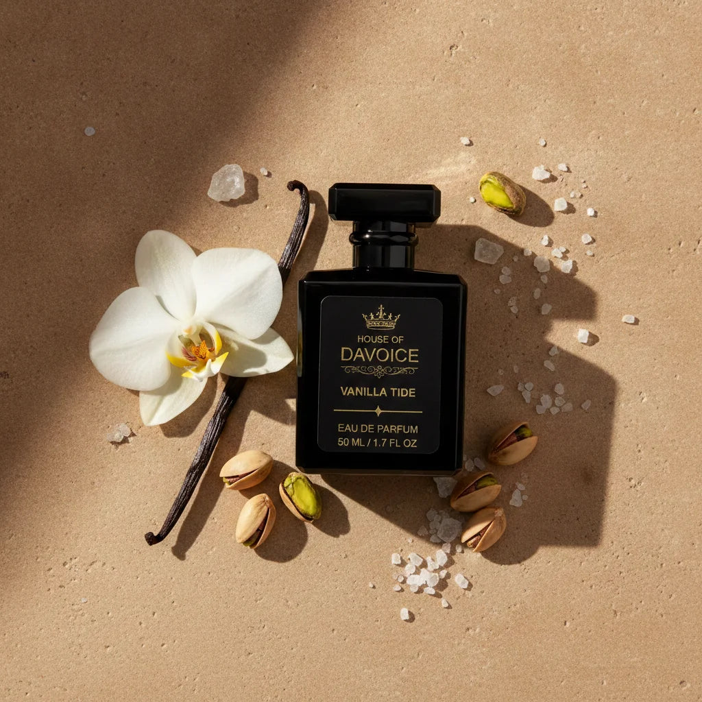 A perfume bottle labeled 'House of DaVoice Vanilla Tide Eau de Parfum' is arranged on a warm beige surface with a white flower, vanilla bean, pistachios, and sea salt scents