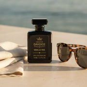 Vanilla Tide luxury perfume beside sunglasses and linen near the ocean